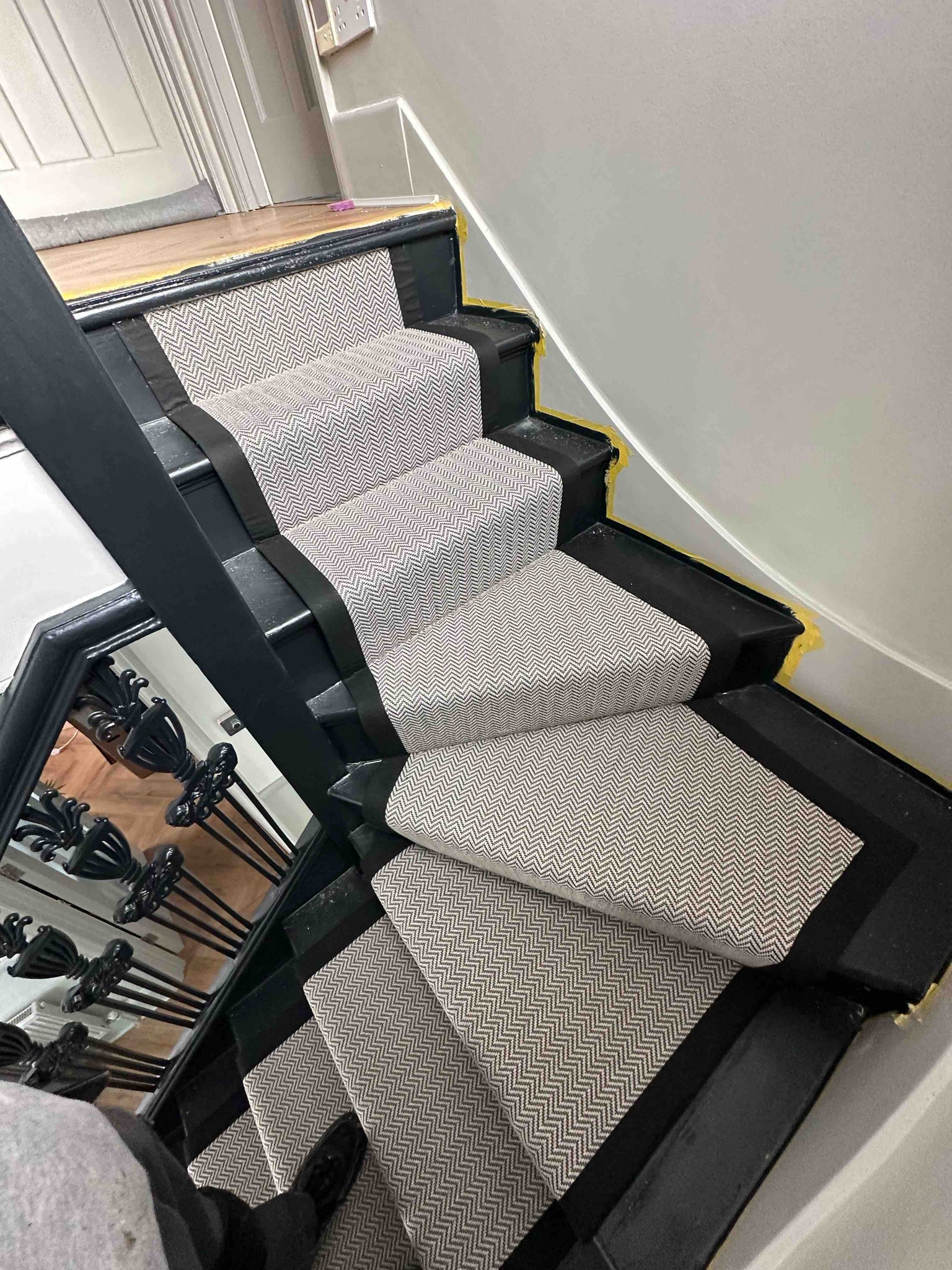How the black and white herringbone patterned looks when it is fitted to winding stairs
